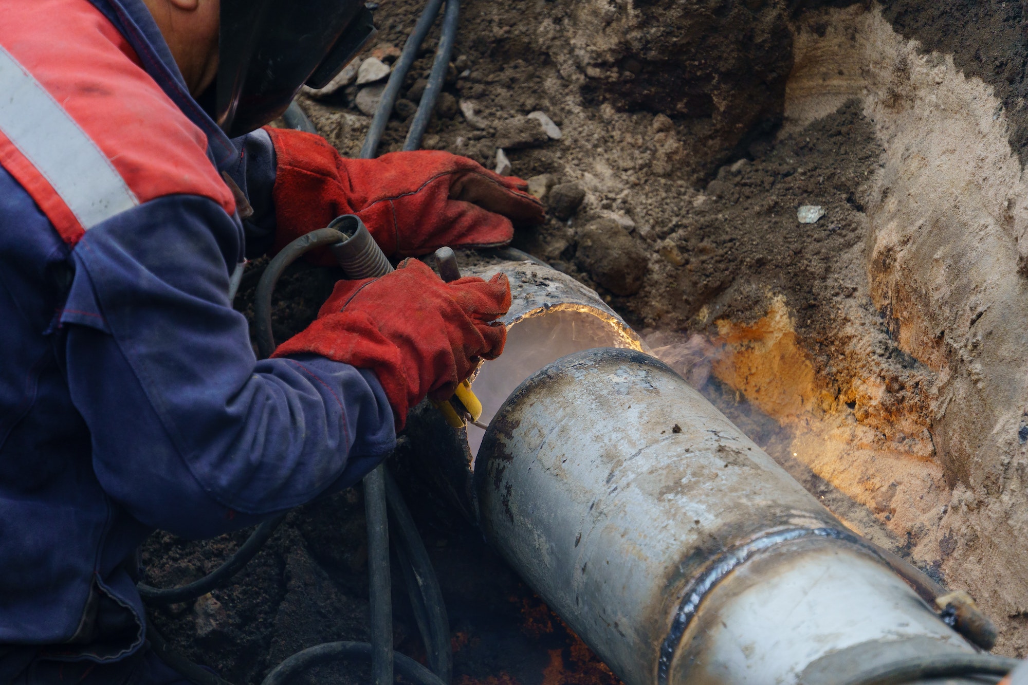 Close up of utility worker fixing broken water main. Sewerage pipe repair concept. Top view.